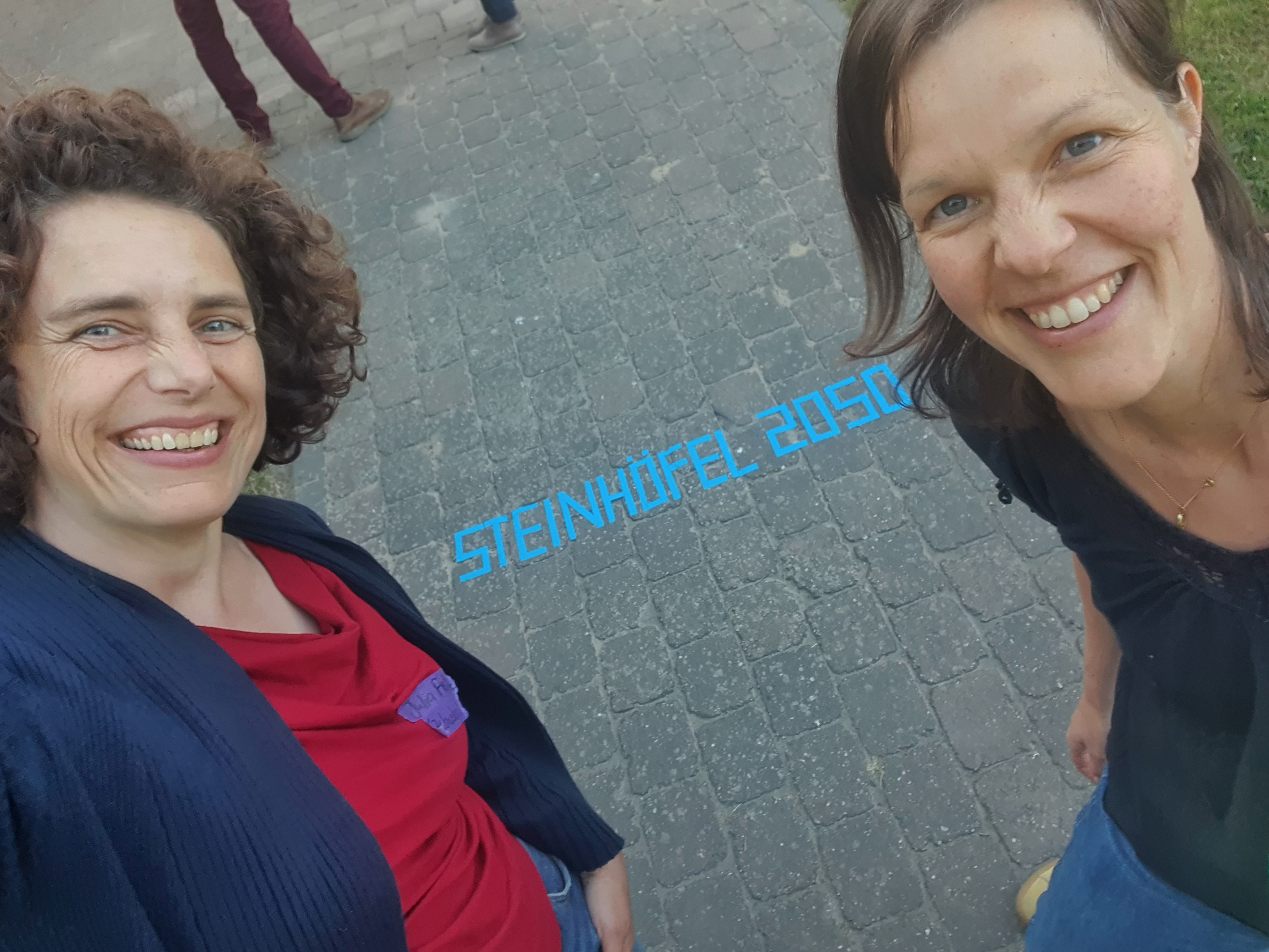 Unsere Kolleginnen Julia Filitz und Carolin Holtkamp machen ein Selfie mit dem aufgeklebten Schriftzug "Steinhöfel 2050"