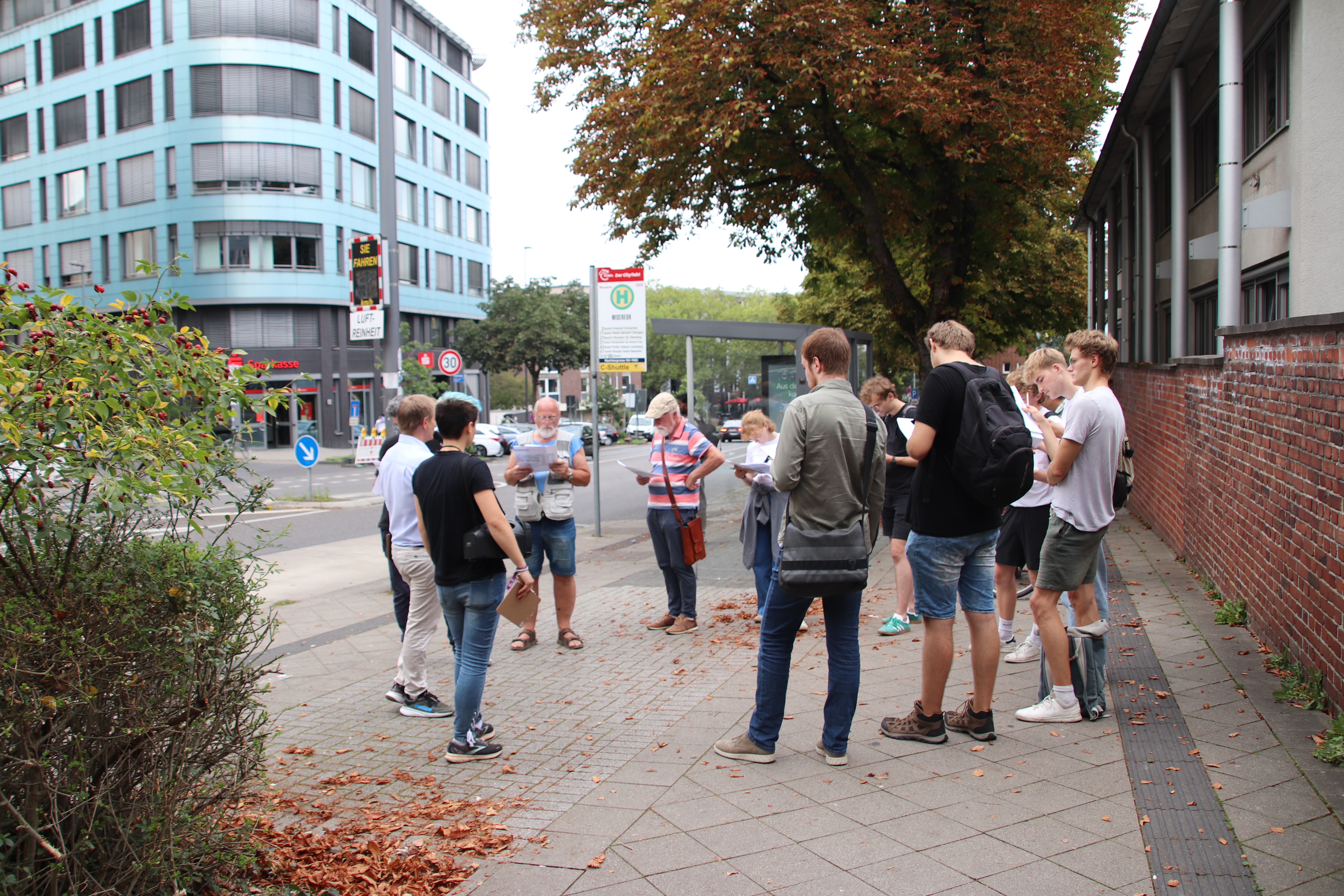 Eine kleine Gruppe Besucher*innen beim Trassenspaziergang in Aachen mit Plänen in der hand.